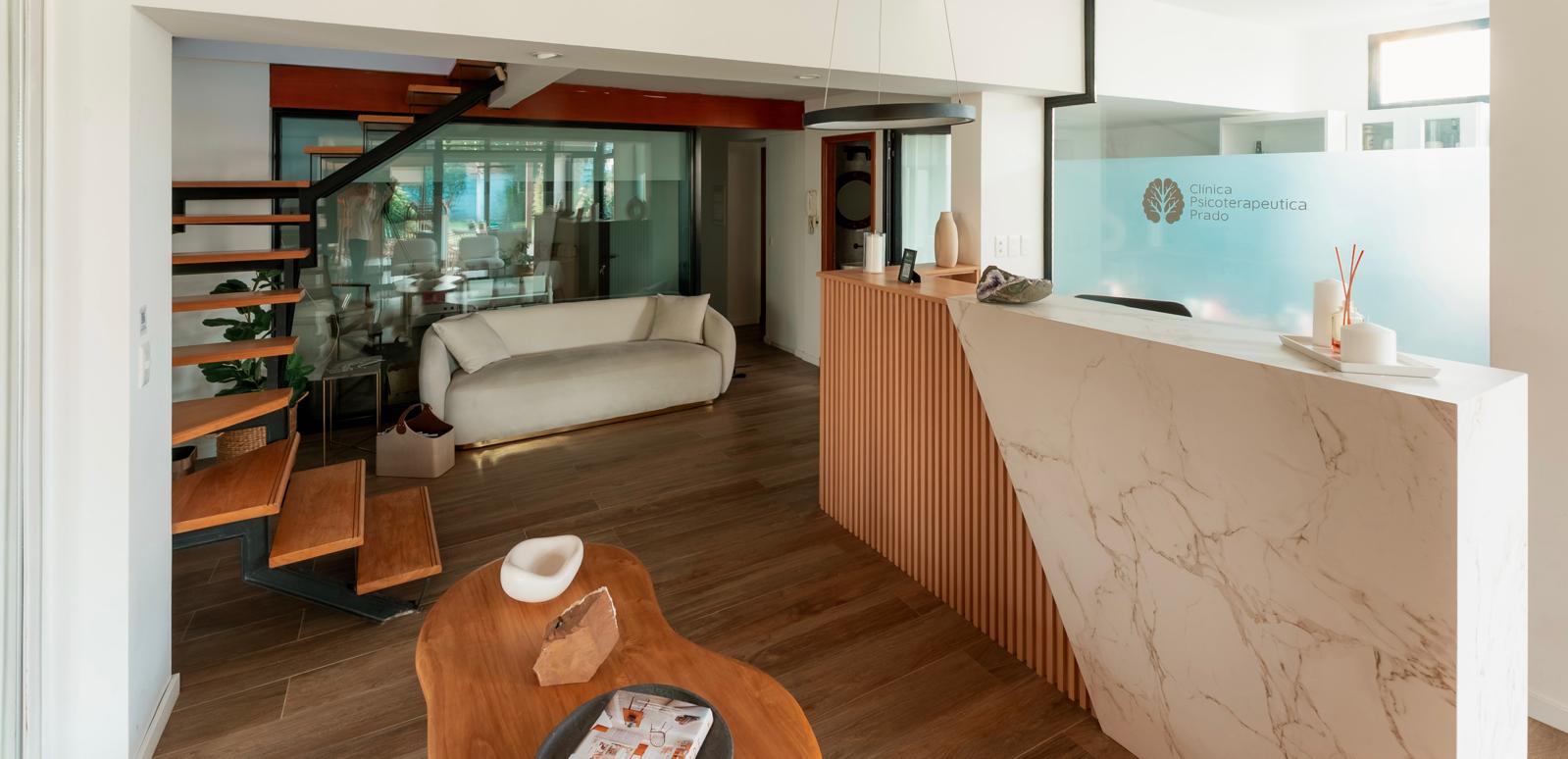 Recepción de la Clínica Psicoterapéutica Prado — espacio moderno con mármol, madera y luz natural